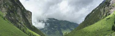 Panoramaaufnahme eines grünen Tales unter bewölktem Himmel