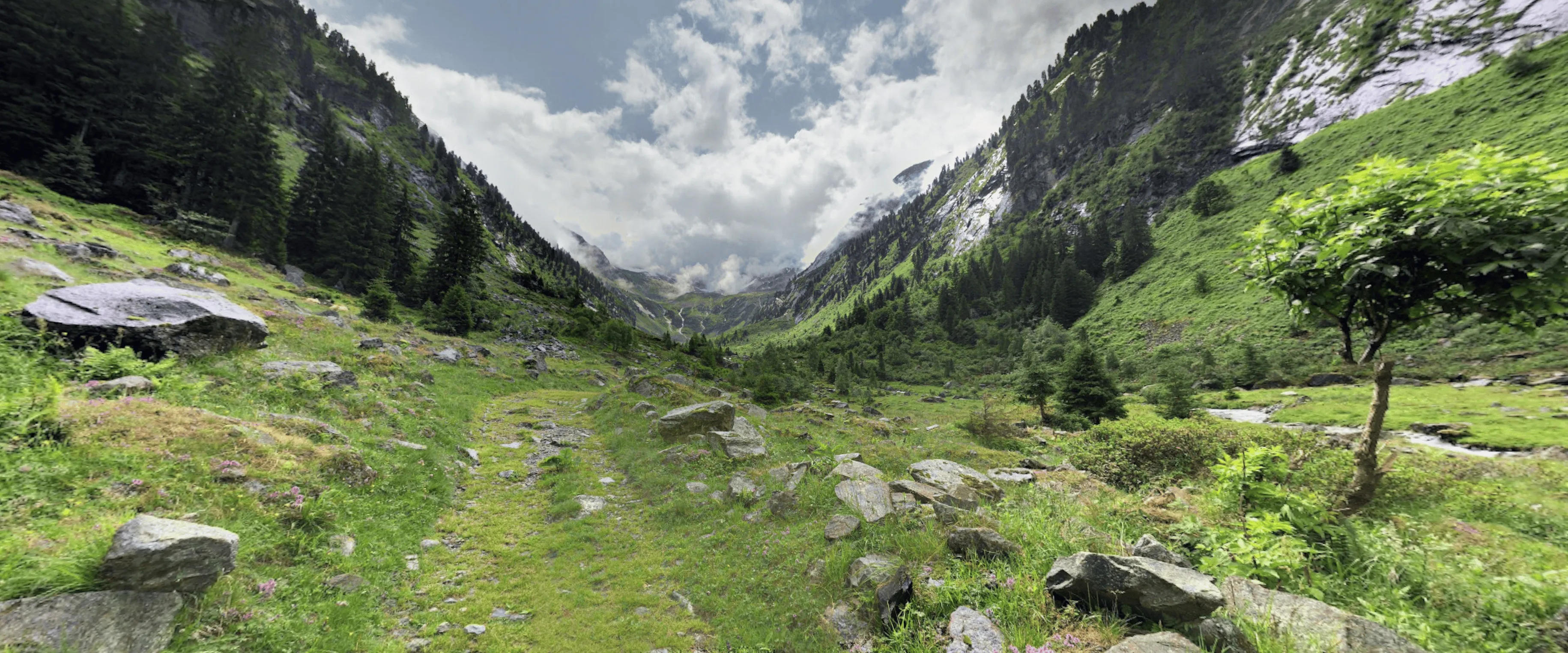 Berglandschaft mit einem grünen Tal und Wolken am Himmel